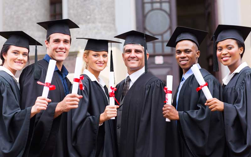 group of young people holding diplomas in their caps and gowns.