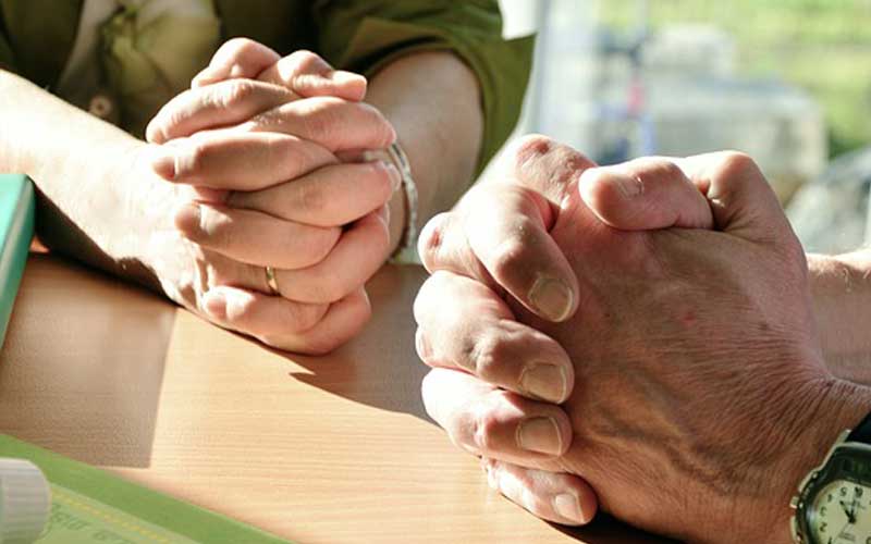 male and female hands clasped in prayer.